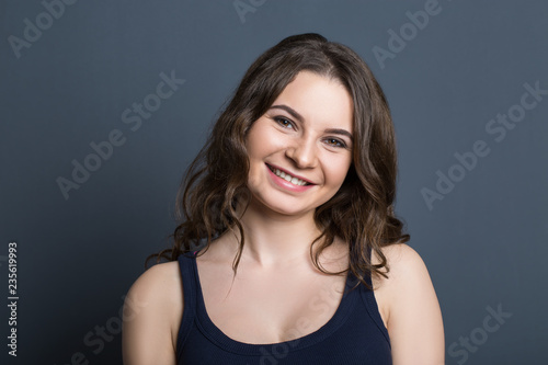Beautiful young girl on a gray background smiling