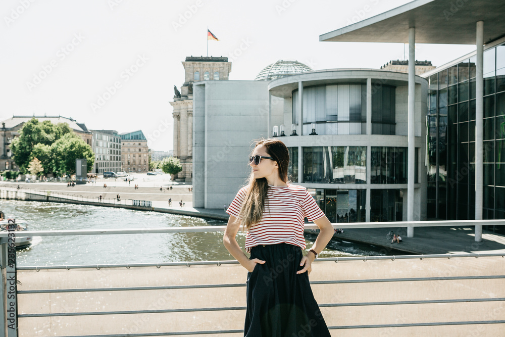 Young beautiful girl on the street of Berlin. Lifestyle. In the background  is the architecture of Berlin in Germany. Stock Photo | Adobe Stock
