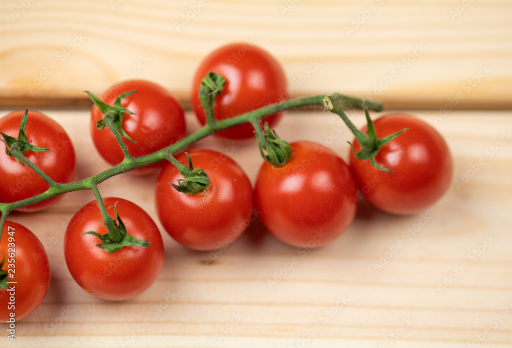 Tomatoes cherry branch isolated on wooden background Tomatoes cherry branch isolated on wooden background