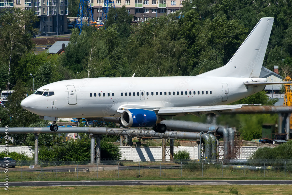 White modern twin engine passenger airplane landing at international airport White modern twin engine passenger airplane landing at international airport