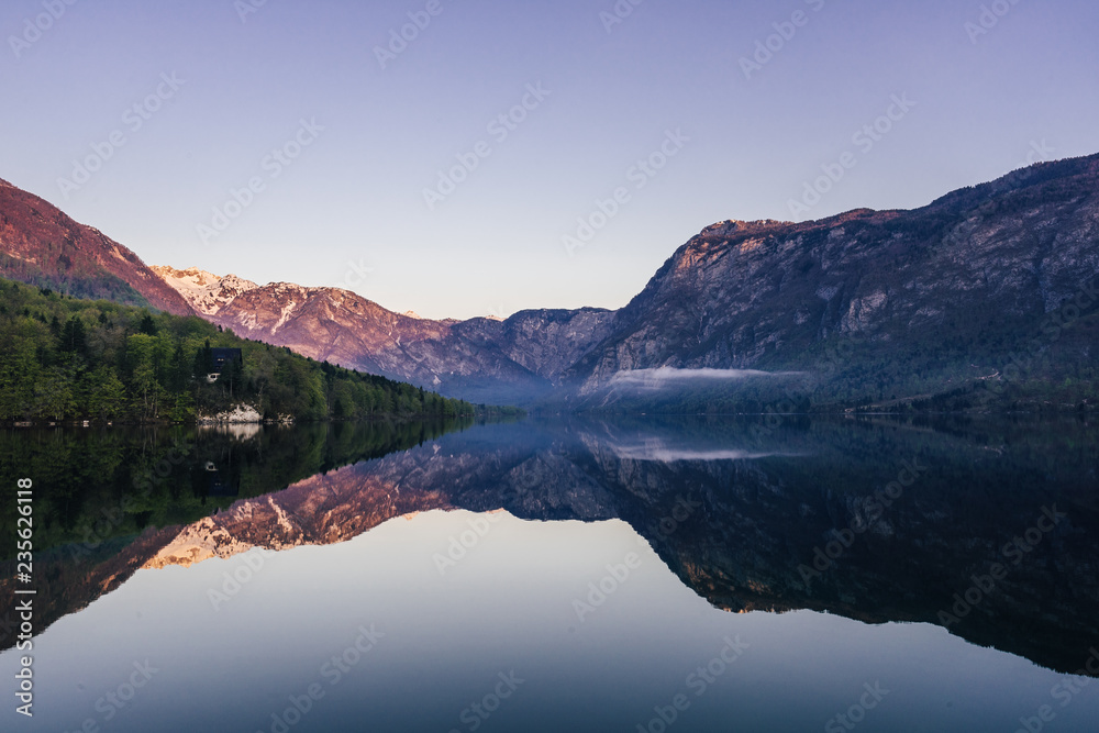 Sunrise view of alpine lake Bohinj with blue sky, sunlight and mist over water. Circles in water. Famous lake of Bohinj in Triglav National Park, Julian alps, Slovenia.