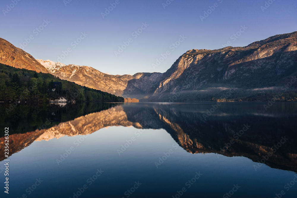 Sunrise view of alpine lake Bohinj with blue sky, sunlight and mist over water. Circles in water. Famous lake of Bohinj in Triglav National Park, Julian alps, Slovenia.