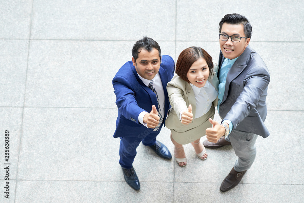 High angle view of multiethnic group of business people standing and showing thumbs up