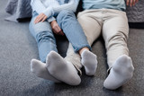 cropped view of couple sitting on floor with crossed legs
