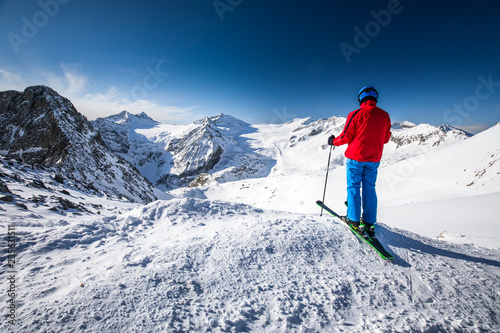 Young happy attractive skier on the top of mountains enjoying the view from Presena Glacier, Tonale, Italy