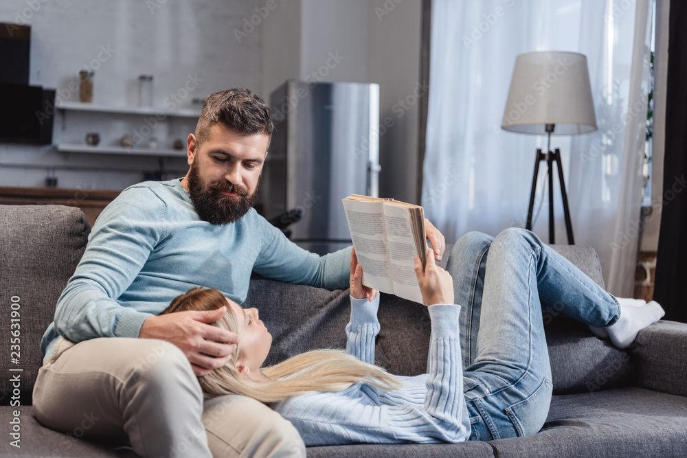  Wife reading book and lying on knees of handsome husband