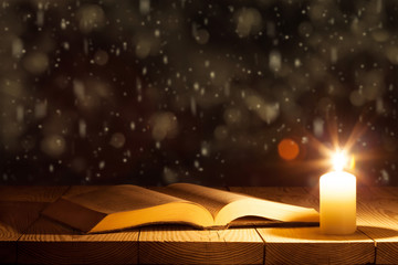 a bible on the table in the light of a candle