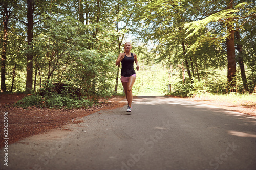 Fit young blonde woman running alone on a forest path © Flamingo Images