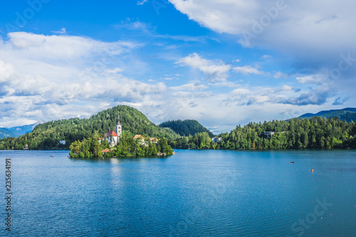 Beautiful view of blue Lake Bled, Slovenia, on a sunny day, blue sky and white clouds, church on the island.