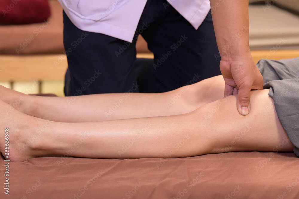 Professional therapist giving traditional thai leg and body massage to a woman in spa