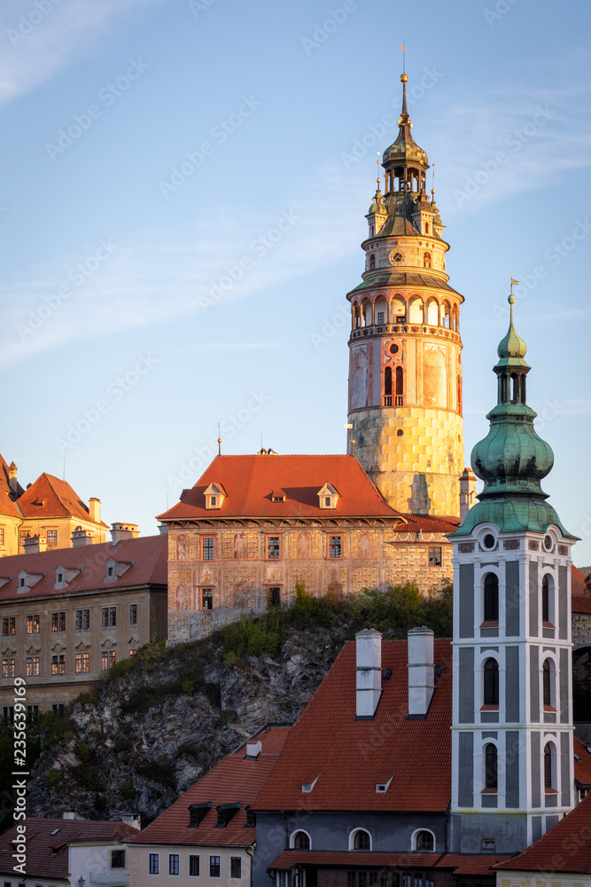 View of the State Castle and Chateau Cesky Krumlov, tower of St. Jost church and historic red roof houses in Cesky Krumlov, Czech Republic, during morning sunrise