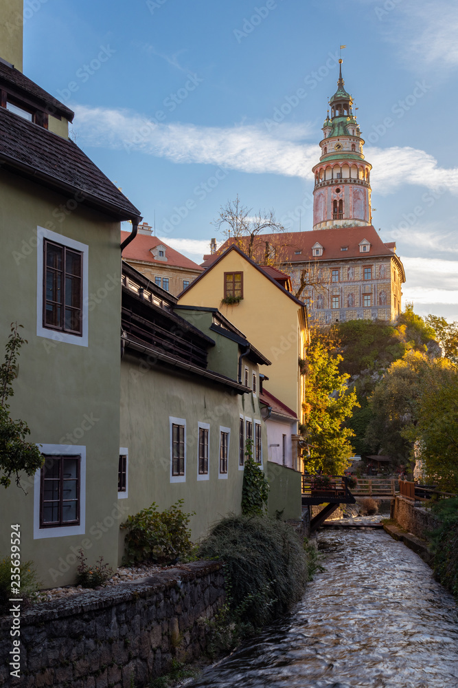 View of the tower of State Castle and Chateau Cesky Krumlov and historic houses in Cesky Krumlov, Czech Republic, during morning sunrise
