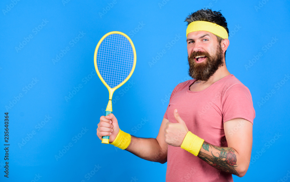 Athlete hold tennis racket in hand on blue background. Tennis sport and  entertainment. Tennis club concept. Man bearded hipster wear old school  sport outfit with bandages. Tennis player retro fashion Stock Photo