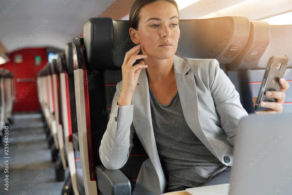 Businesswoman in first class on train looking at cellphone Businesswoman in first class on train looking at cellphone