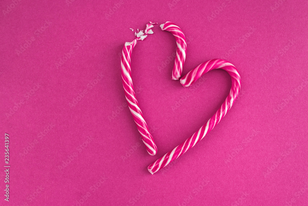 Candy cane broken heart on pink background.