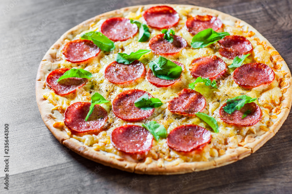 Pepperoni Pizza with Mozzarella cheese, salami, Tomato sauce, pepper, Spices and Fresh Basil. Italian pizza on wooden table background