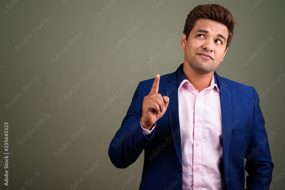Indian businessman wearing suit against colored background Indian businessman wearing suit against colored background