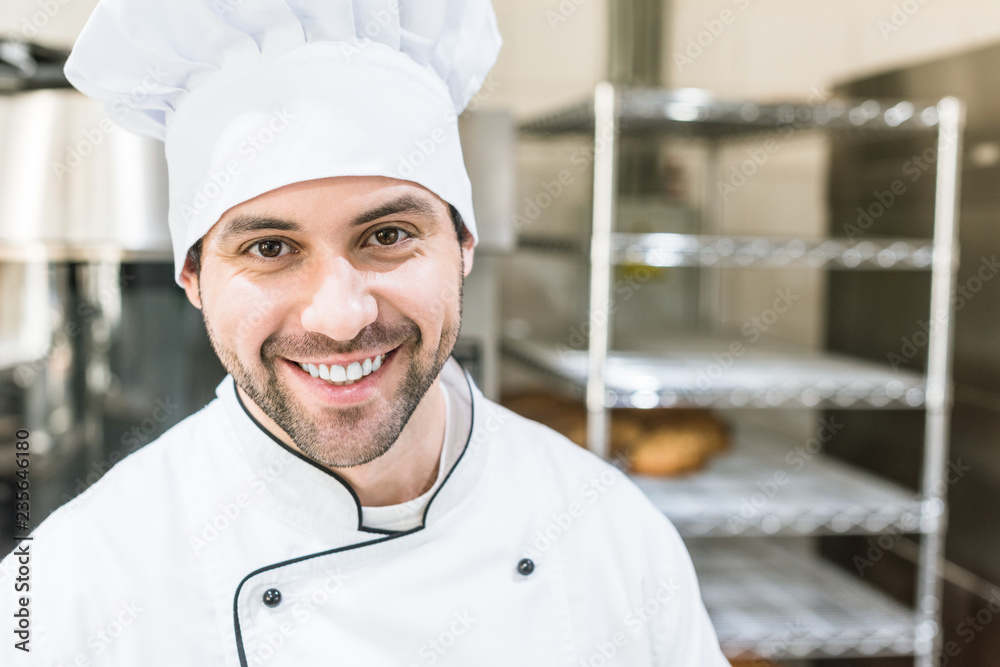 Handsome cook in chefs uniform smiling in bakehouse Handsome cook in chefs uniform smiling in bakehouse