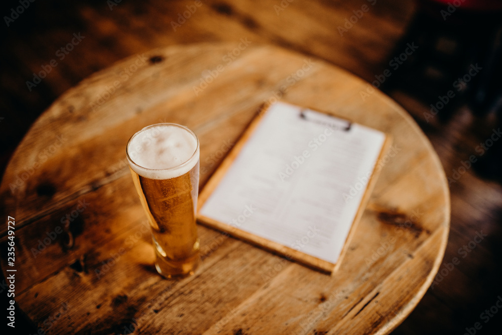 Close up of beer pint on a wooden table, with beverage cart on the right.