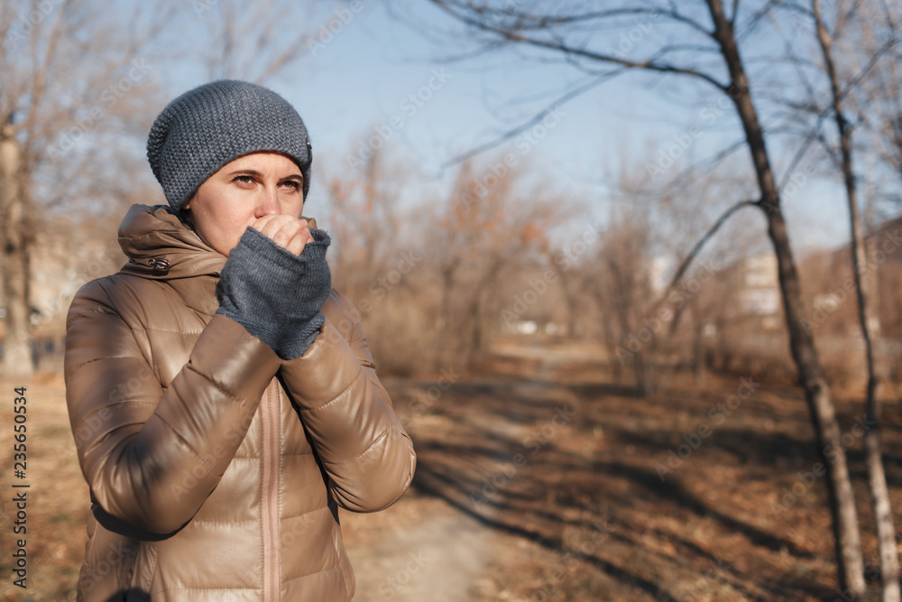 The woman froze in the park. Heats hands breath The woman froze in the park. Heats hands breath