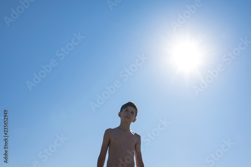 Silhouette of teen boy on the beach opposite sun. Concept