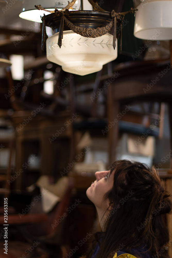 Young girl looking at a retro lamp in an antique shop