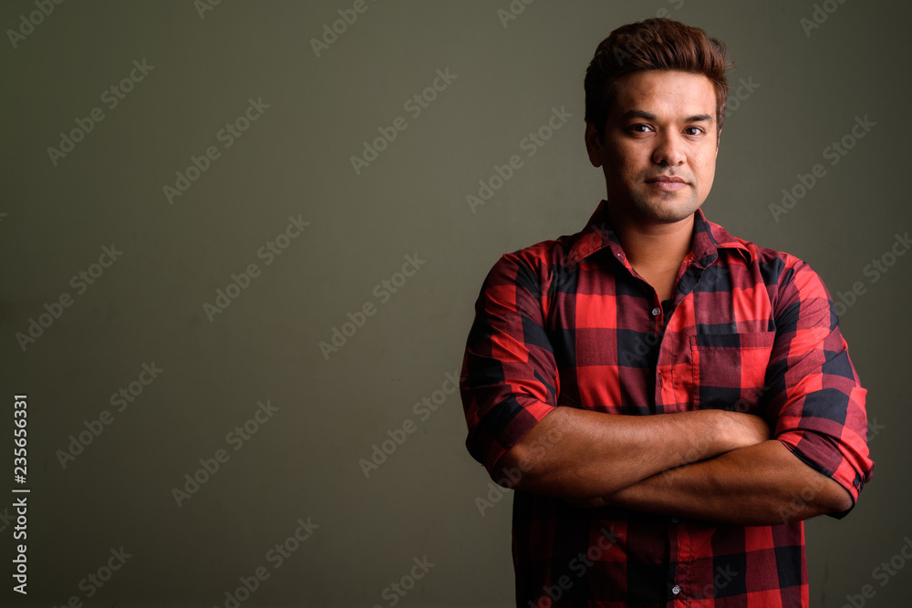 Indian man wearing red checkered shirt against colored backgroun Indian man wearing red checkered shirt against colored backgroun