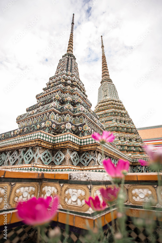 Fototapeta premium Vertical photo with flowers of Wat Pho or Temple of the Reclining Buddha in Bangkok, Thailand. One of the most attractive landmark in Thailand.