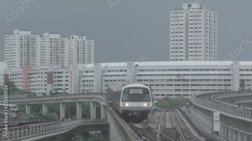 Modern subway train on a railroad in Sinapore on a city buildings background. Shot. Singapore mass rapid train MRT travels on the track. photo