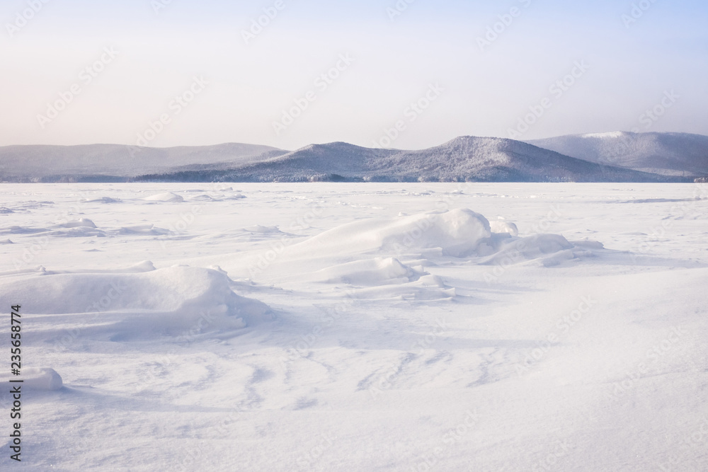 Beautiful landscape of frozen lake covered with snow and ice. Turgoyak Lake in Southern Urals, Russia.