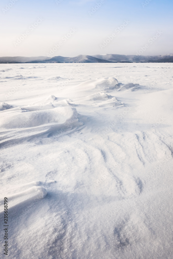 Beautiful landscape of frozen lake covered with snow and ice. Turgoyak Lake in Southern Urals, Russia.