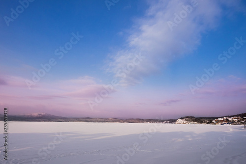 Beautiful landscape of frozen lake covered with snow and ice. Turgoyak Lake in Southern Urals, Russia.