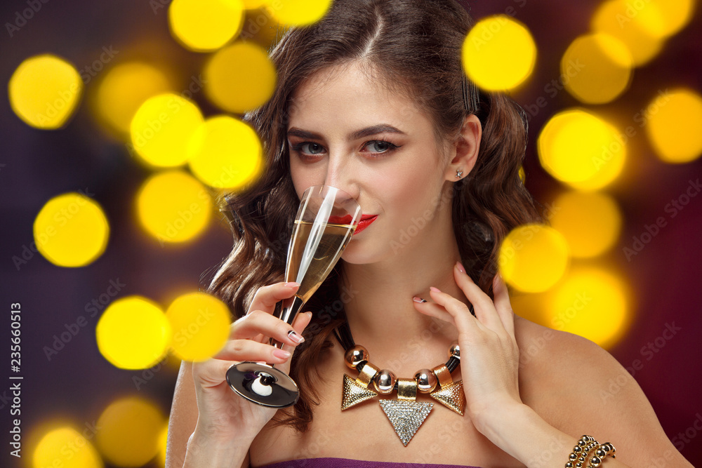 Beautiful girl holding a glass of champagne. Festive mood, shiny background with lights . Celebration of New Year and Christmas, white wine and excitement Beautiful girl holding a glass of champagne. Festive mood, shiny background with lights . Celebration of New Year and Christmas, white wine and excitement