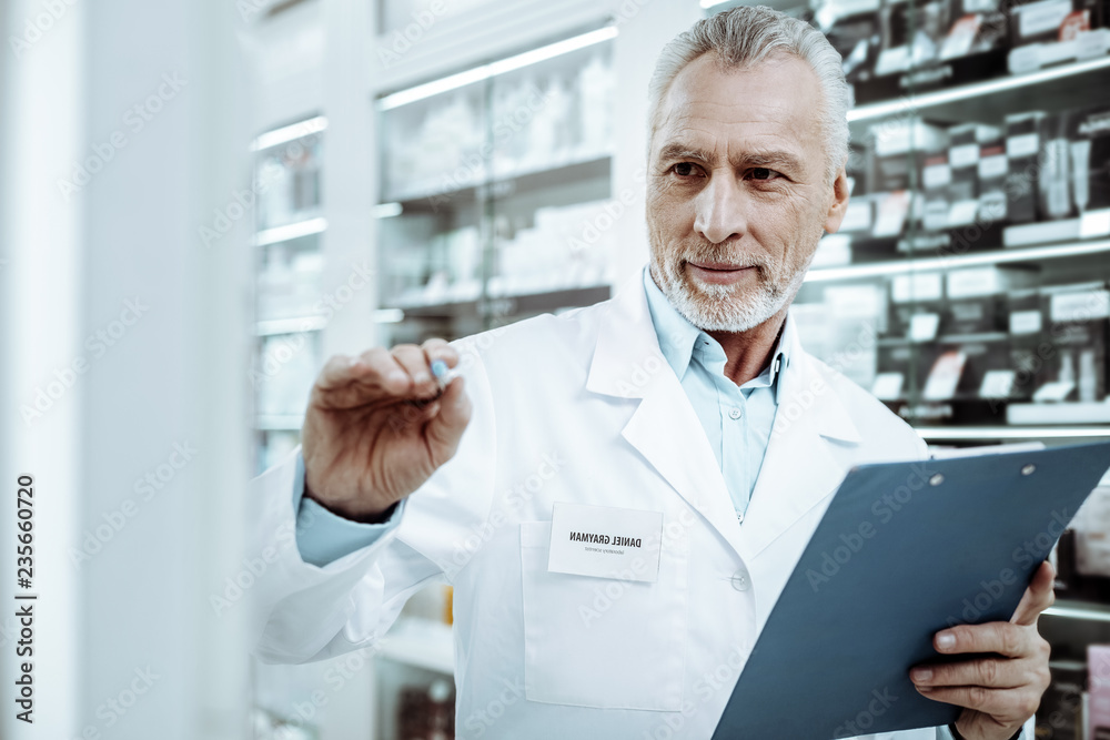 Attentive senior pharmacist working consciously in drugstore Attentive senior pharmacist working consciously in drugstore