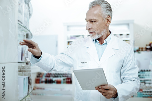 Positive delighted pharmacist talking package with pills