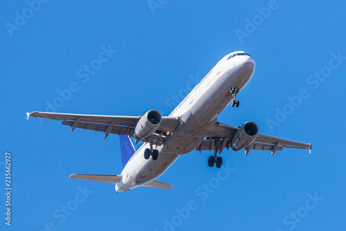 A white airplane flying in a clear pale blue sky