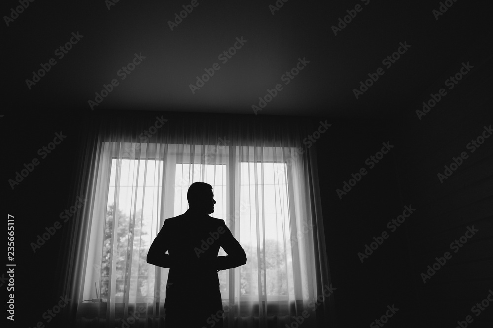 Man stand in front of window. Silhouette of young man. Black and white picture