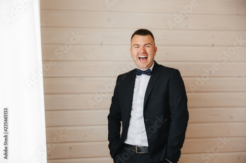 Happy young man smile. He stand near the windor and have fun photo