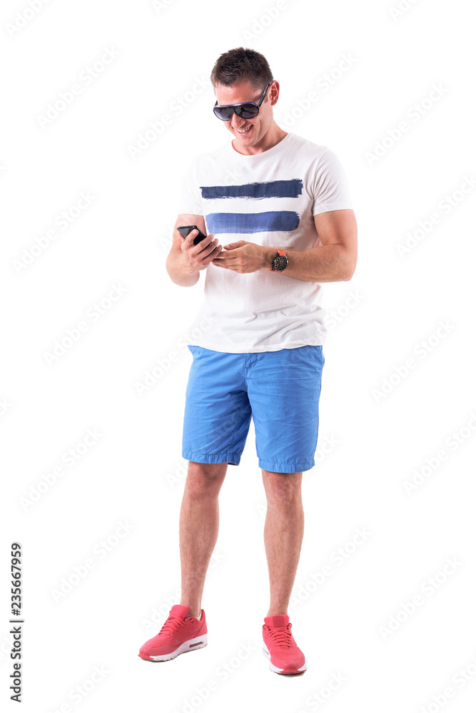 Smiling relaxed happy man using mobile phone in summer clothes. Full body isolated on white background. 
