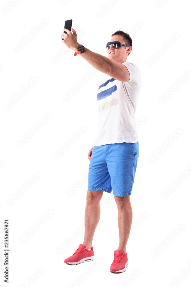 Happy smiling man tourist in summer clothes taking high angle selfie photos. Full body isolated on white background. 
