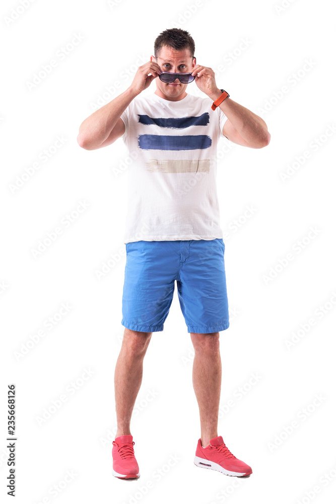 Serious macho tough guy removing or applying sunglasses staring at camera. Full body isolated on white background. Serious macho tough guy removing or applying sunglasses staring at camera. Full body isolated on white background.