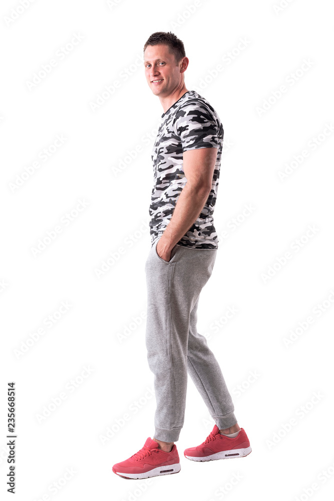 Happy relaxed young adult sporty man walking and smiling at camera. Full body isolated on white background. Happy relaxed young adult sporty man walking and smiling at camera. Full body isolated on white background.
