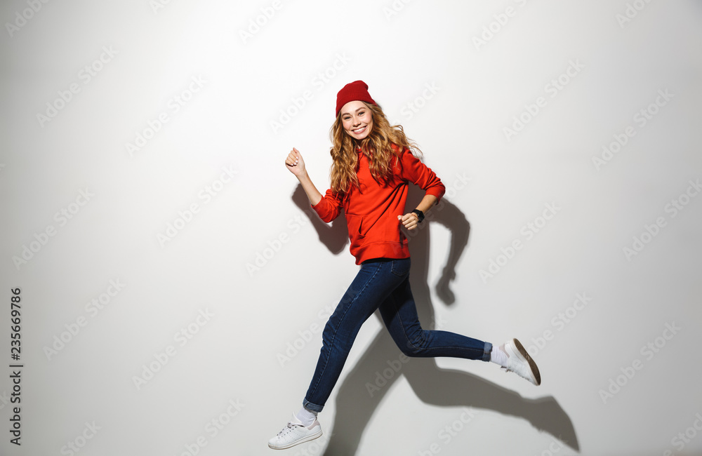 Full length portrait of an excited girl wearing hoodie jumping