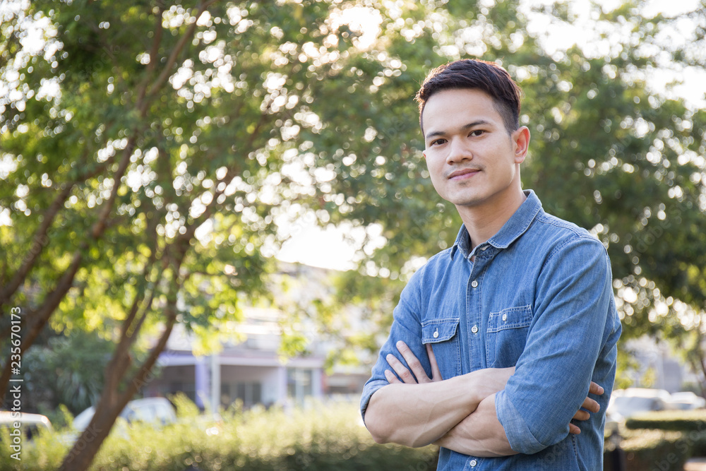 Portrait of a casual dressed young on nature background, Asian man confidently standing in the garden Portrait of a casual dressed young on nature background, Asian man confidently standing in the garden