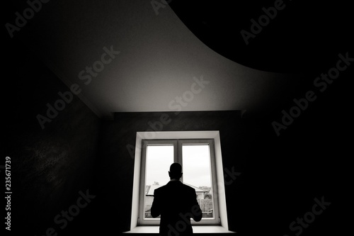 silhouette of man looking through window