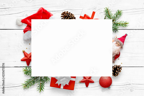 New Year's scene with free space for greeting text on white paper and Christmas decorations in background. White wooden table in background.