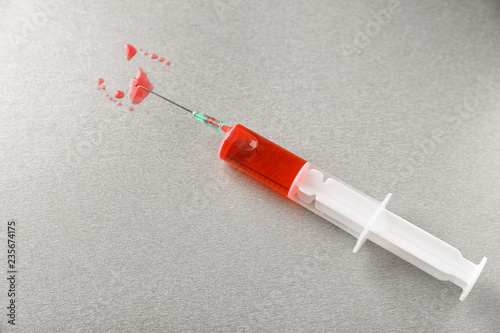 Syringe with color liquid on grey background