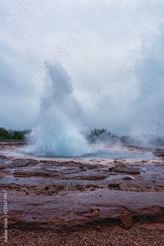 Magnificent Strokkur Geyser erupts the fountain of azure water, popular tourist attraction, Haukadalur geothermal area, Iceland. Vertical image