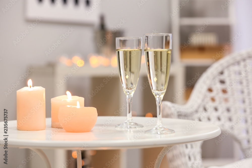 Glasses of champagne with burning candles on white table Glasses of champagne with burning candles on white table