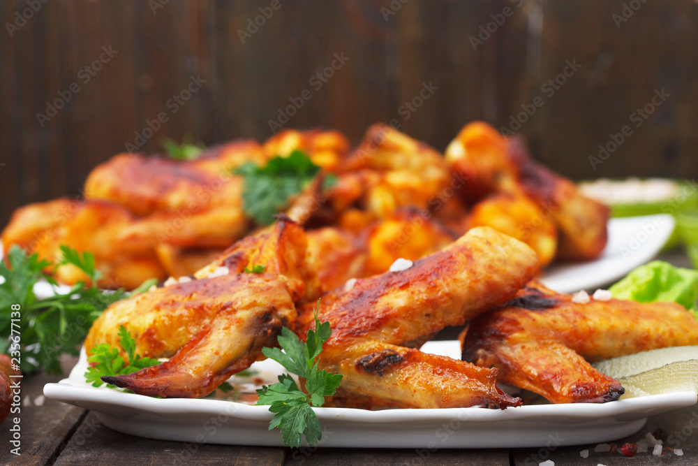 Crispy grilled chicken wings on a white plate. Tasty, homemade food.
